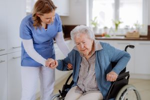 Nurse,Helping,Senior,Woman,To,Stand,Up,From,Wheelchair.