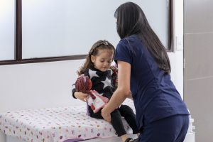 Doctor seating a girl on a medical examination table, with copy space.